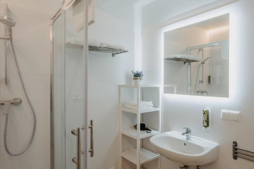 a white bathroom with a sink and a shower at Chill & Relax Apartments in Neusiedl am See in Neusiedl am See