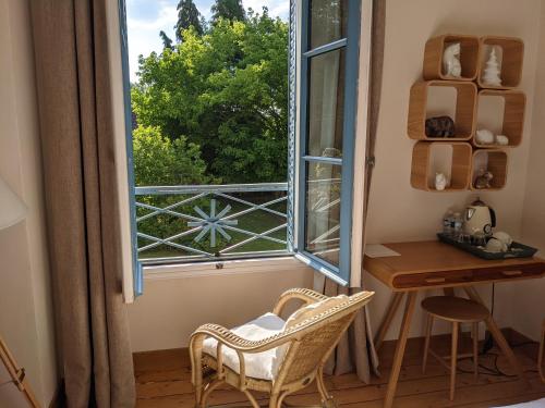 an open window with a desk and a chair next to a table at La Closerie in Droue-sur-Drouette