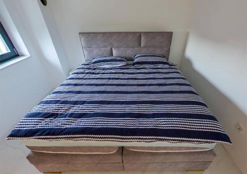 a bed with a blue and white striped blanket on it at Plitvice House Lina in Rakovica