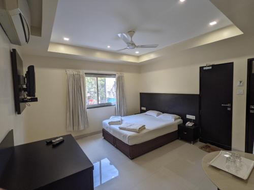 a bedroom with a bed and a desk and a window at Hotel Sri Kamal International in Solapur