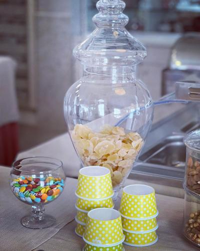 a glass jar filled with candy next to a pile of cups at Hotel Ardea in Riccione