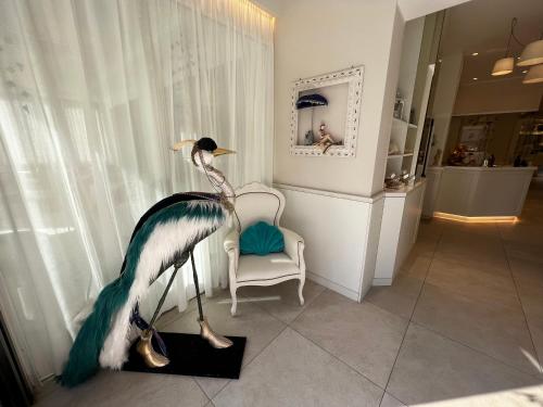 a statue of a peacock in a room with a chair at Hotel Ardea in Riccione