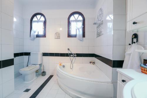 a white bathroom with a tub and a toilet at Villa Kalma in Trílofon