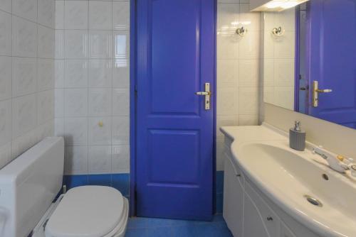 a blue door in a bathroom with a toilet and a sink at DEJA BLUE Maisonette ll in Kokkari