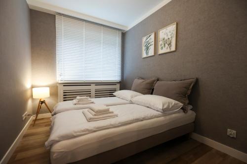 um quarto com uma grande cama branca e uma janela em Villa Park Apartament em Ostróda
