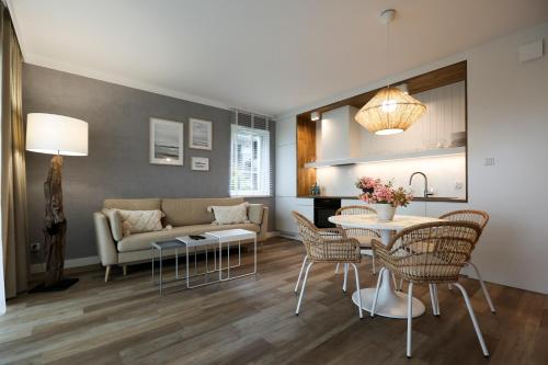uma sala de estar com um sofá, uma mesa e cadeiras em Villa Park Apartament em Ostróda