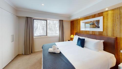 a bedroom with a large bed with a teddy bear on it at Lodge Apartment 25 The Stables in Perisher Valley