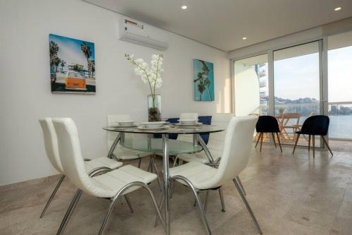 a dining room with a glass table and white chairs at Luxury apartment in front of Acapulco Beach in Acapulco