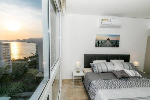 a bedroom with a bed and a view of the ocean at Luxury apartment in front of Acapulco Beach in Acapulco