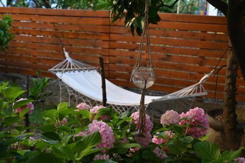 a swinging hammock in a garden with pink flowers at Hostel Center in Ulcinj