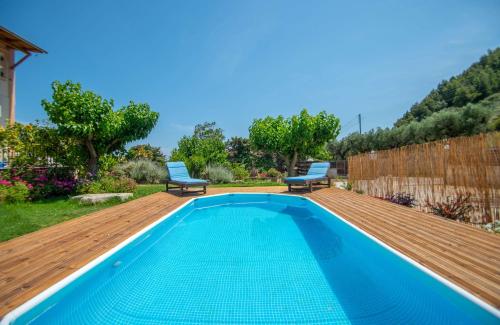 a swimming pool with a wooden deck next to a yard at Family Private Homes & Sea View in Lithakia