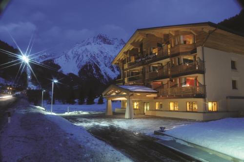 a building in the snow at night with a mountain at Hotel Garni Pegrà in Ponte di Legno