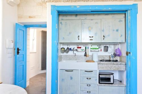 uma cozinha com armários brancos e uma porta azul em Apartment Attico panoramico di Martina Franca em Martina Franca