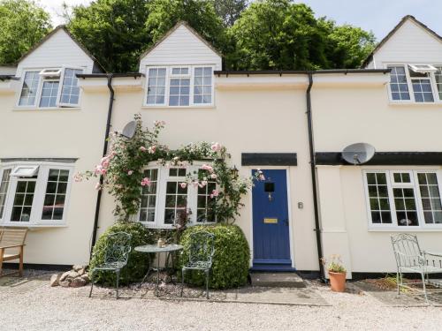 a white house with a blue door and chairs at 5 Wye Rapid Cottages in Ross on Wye