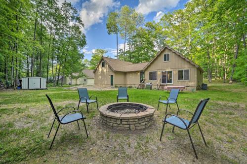 a group of chairs around a fire pit in front of a house at Higgins Lake Getaway - Boating, Fish, Golf, ATV! in Roscommon