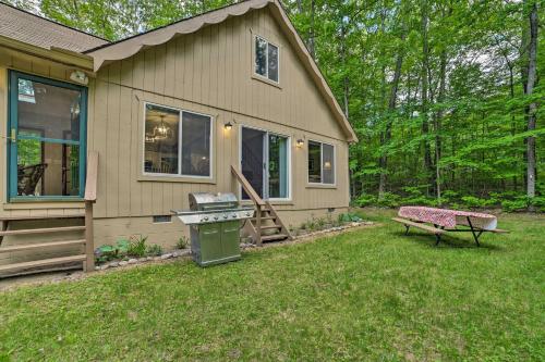 a house with a grill and a bench in the yard at Higgins Lake Getaway - Boating, Fish, Golf, ATV! in Roscommon