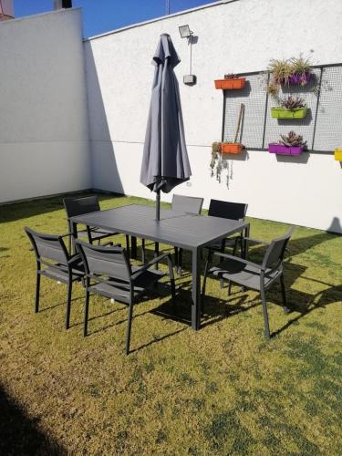 a table and chairs with an umbrella on the grass at Mendoza is life in Guaymallen