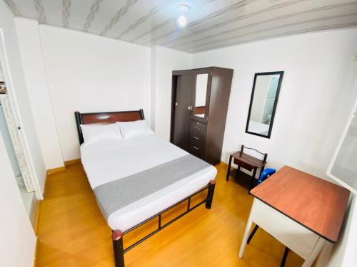 Dormitorio pequeño con cama y mesa en casa coral, en Bogotá
