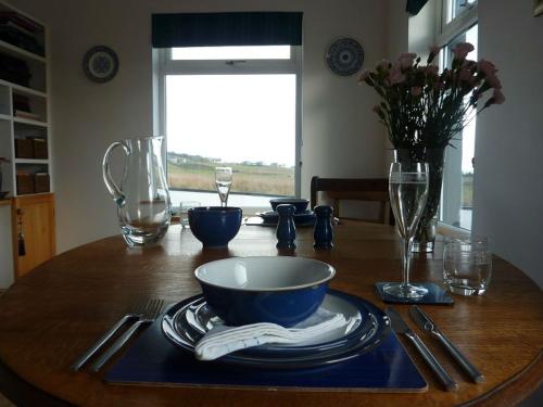 a wooden table with a bowl and plates on it at Taigh Geal in Stornoway