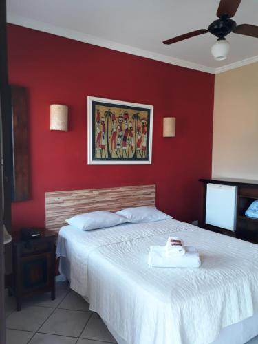 una camera con un letto bianco con una parete rossa di Pousada Estacao do Sol de Paraty a Parati