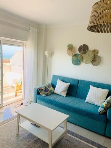 uma sala de estar com um sofá azul e uma mesa em Apartamento T1 Monte Gordo em Monte Gordo
