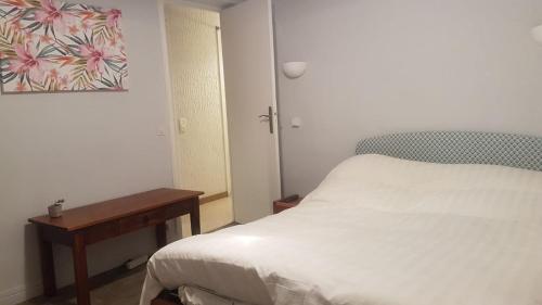 a bedroom with a white bed and a table at 1er etage privatif dans une maison in La Colle-sur-Loup