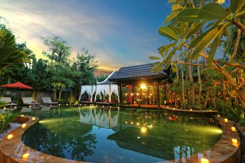 
a large swimming pool with a large fountain in the middle of it at Villa Indochine D'angkor in Siem Reap
