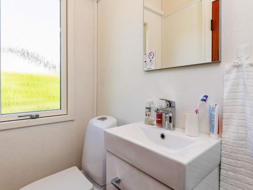 uma casa de banho com um lavatório, um WC e uma janela. em Holiday home Faxe Ladeplads VII em Fakse Ladeplads
