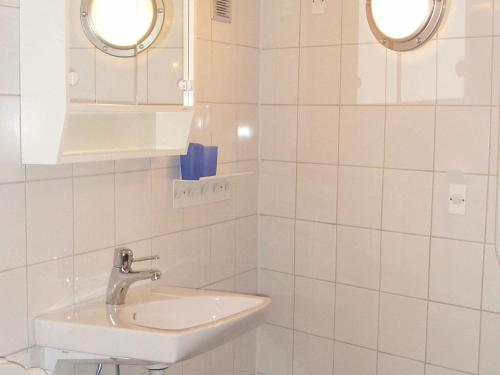 a white tiled bathroom with a sink and two mirrors at Two-Bedroom Holiday home in Kärna 1 in Lycke