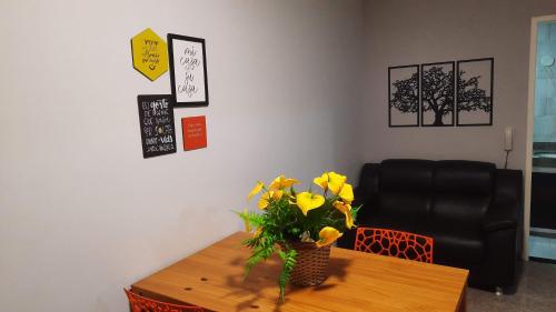 a room with a table with a vase of yellow flowers at Vem pra cá! Localização Privilegiada! in Guarapari