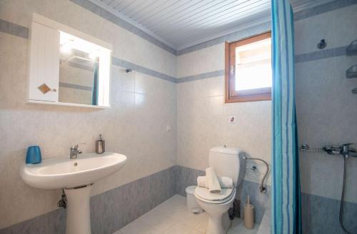 a bathroom with a sink and a toilet and a window at Pine tree Apartment & sunset in Koiliomenos