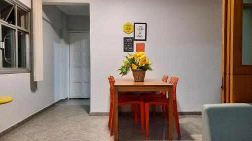 a table with chairs and a vase of flowers on it at Vem pra cá! Localização Privilegiada! in Guarapari
