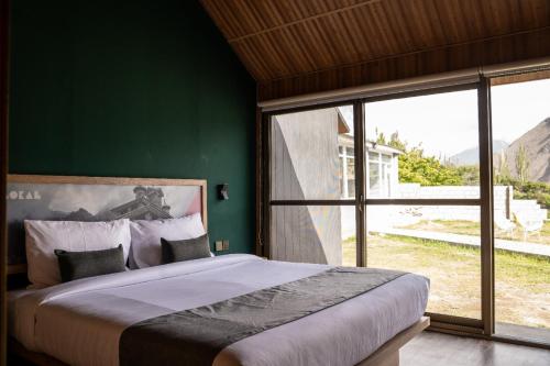 a bedroom with a large bed and a large window at LOKAL Rooms x Hunza (5 Peaks) in Baltit