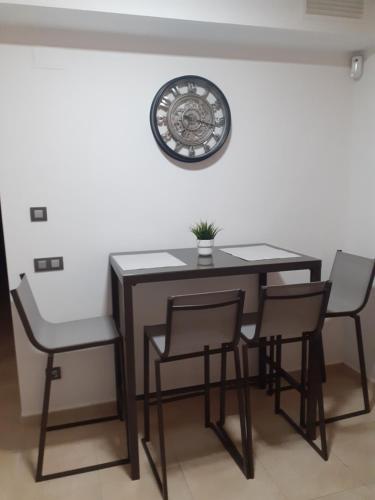 uma mesa de jantar e cadeiras com um relógio na parede em Casa Primi em La Nucía