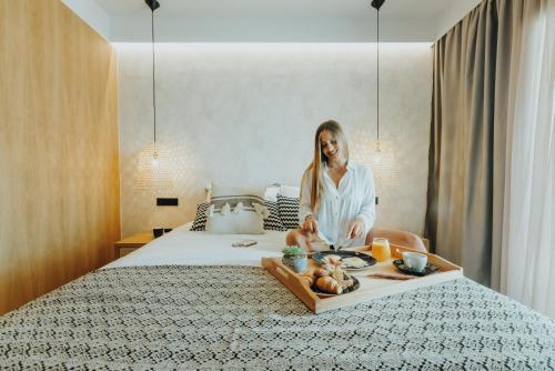 a woman sitting on a bed with a tray of food at Villa veranda in Plaka