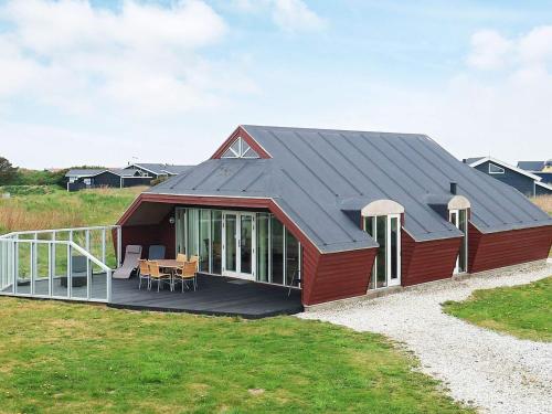 een rood huis met een terras en een tafel bij 8 person holiday home in L kken in Løkken