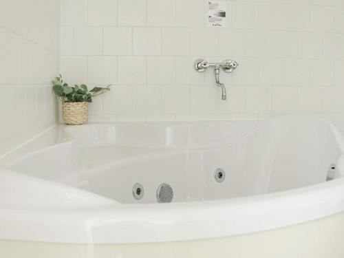 baño con bañera blanca con planta en Four-Bedroom Holiday home in Gjern 1, en Gjern