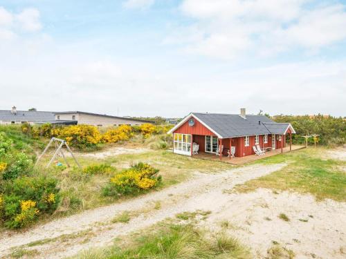 ein rotes Haus mitten auf einem Feld in der Unterkunft 6 person holiday home in Hvide Sande in Nørre Lyngvig