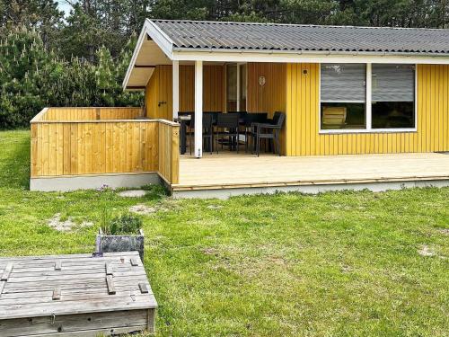 a yellow house with a deck and a table at 5 person holiday home in R dby in Rødby