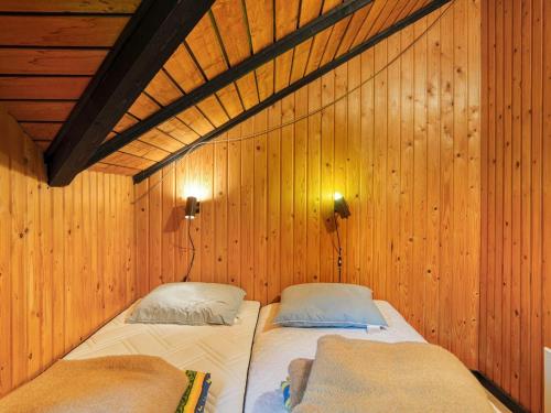 KramnitseにあるThree-Bedroom Holiday home in Rødby 28の木製の壁にベッド2台が備わるベッドルーム1室