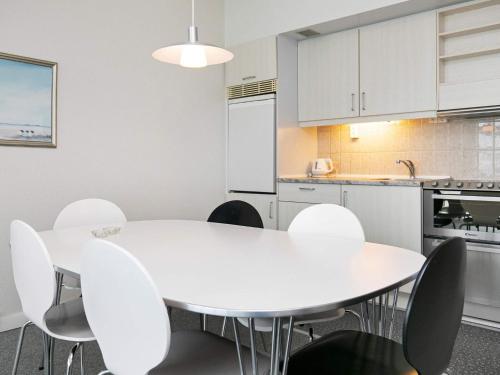 a white kitchen with a white table and chairs at 4 person apartment in holiday park Blokhus in Blokhus