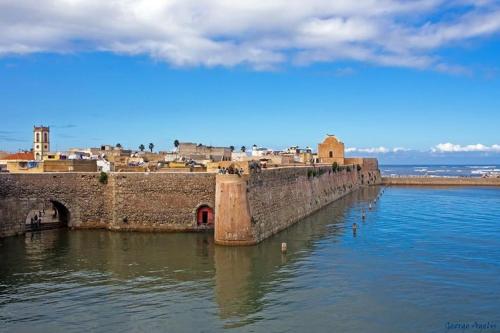 an old castle with a city in the water at Art riad mazighen in El Jadida