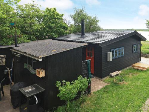 a black shed with a red door and a house at 4 person holiday home in Bogense-By Traum in Bogense