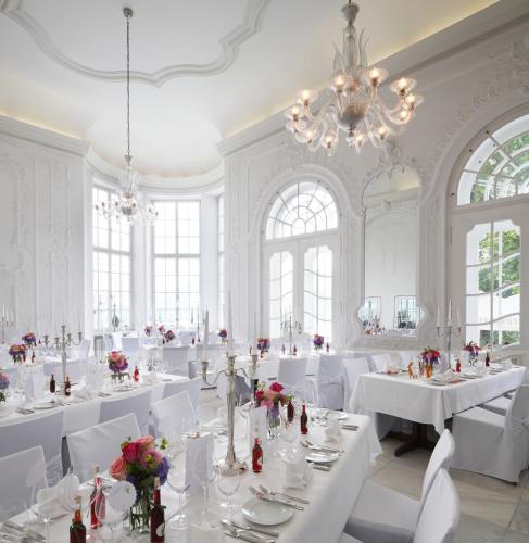 a white dining room with white tables and white chairs at Das Tegernsee in Tegernsee