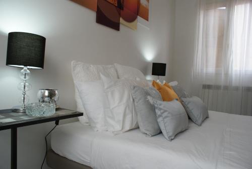 a bed with white pillows and a table with a lamp at 4-Tourist House Bologna-Studio - Self check-in in Bologna