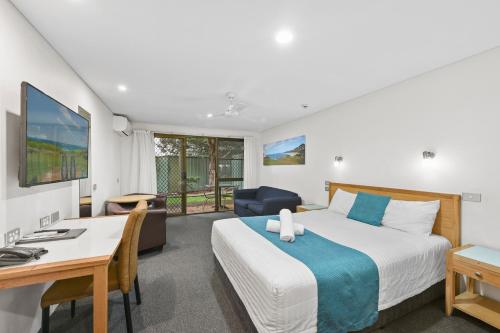 Habitación de hotel con cama, escritorio y silla en Macquarie Barracks Motor Inn, en Port Macquarie