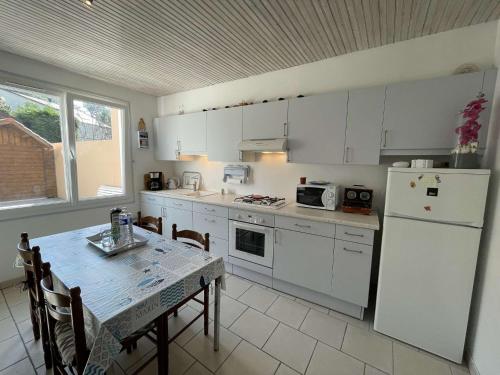 une cuisine avec une table et un réfrigérateur blanc dans l'établissement Charmante maison à Saint-Jean-de-Monts, 400m de la plage, terrasse, jardin, parking et ménage inclus - FR-1-224C-198, à Saint-Jean-de-Monts