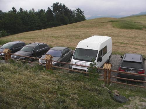 a white van parked next to three cars in a field at Willa Grywałd in Grywałd