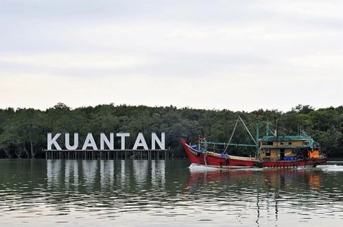 a boat sitting in the water next to a sign at Timurbay Seafront Residence & Suites in Kuantan