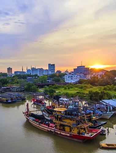 a group of boats docked in a river with a city at Timurbay Seafront Residence & Suites in Kuantan